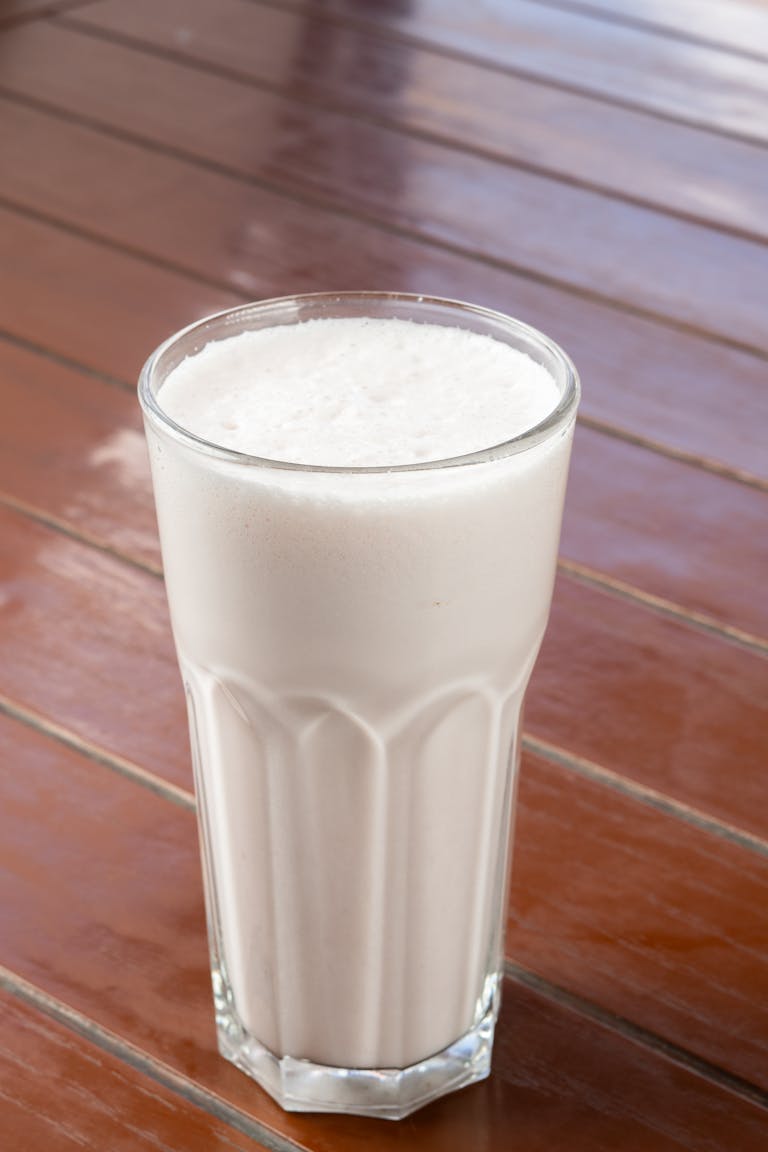 Delicious vanilla milkshake served in a tall glass on a wooden table, perfect for a refreshing treat.