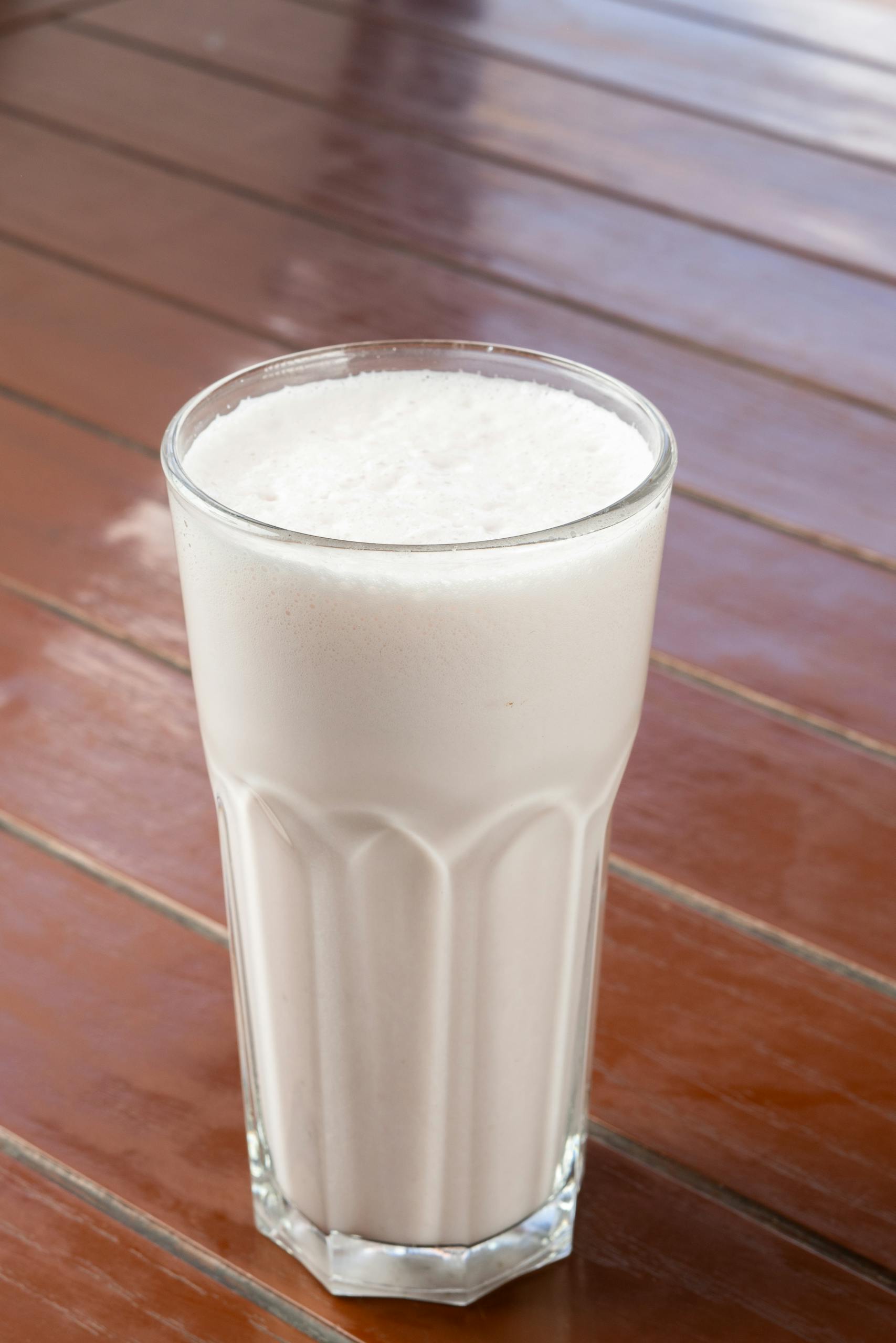 Delicious vanilla milkshake served in a tall glass on a wooden table, perfect for a refreshing treat.